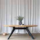 Image capturing the elegance of a styled 2.2-meter oval dining table, boasting a solid oak tabletop atop a sleek black base, timeless design and sophistication.