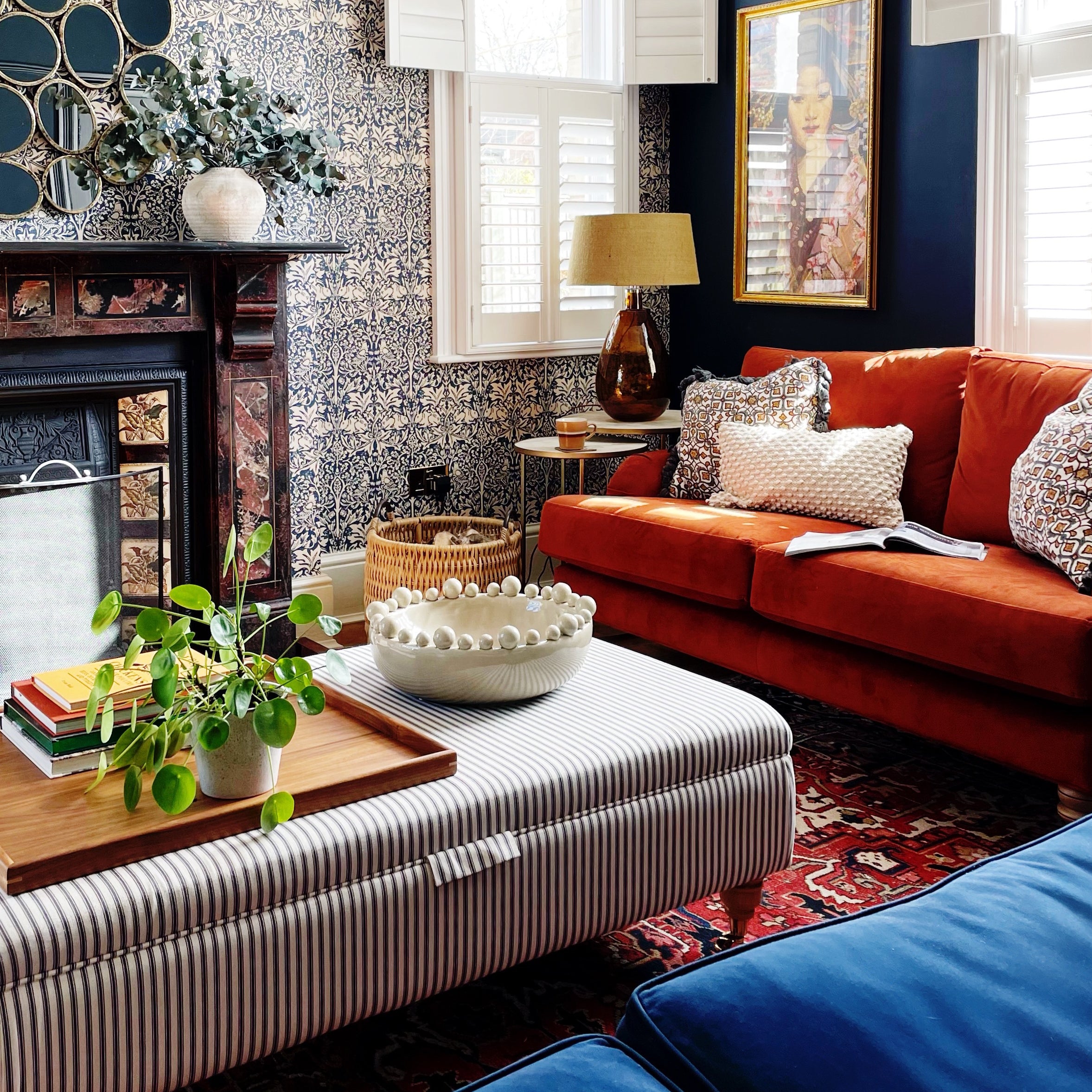A wooden tray for footstool in a stylish living room, featuring books, a potted plant, and decorative elements on an ottoman.