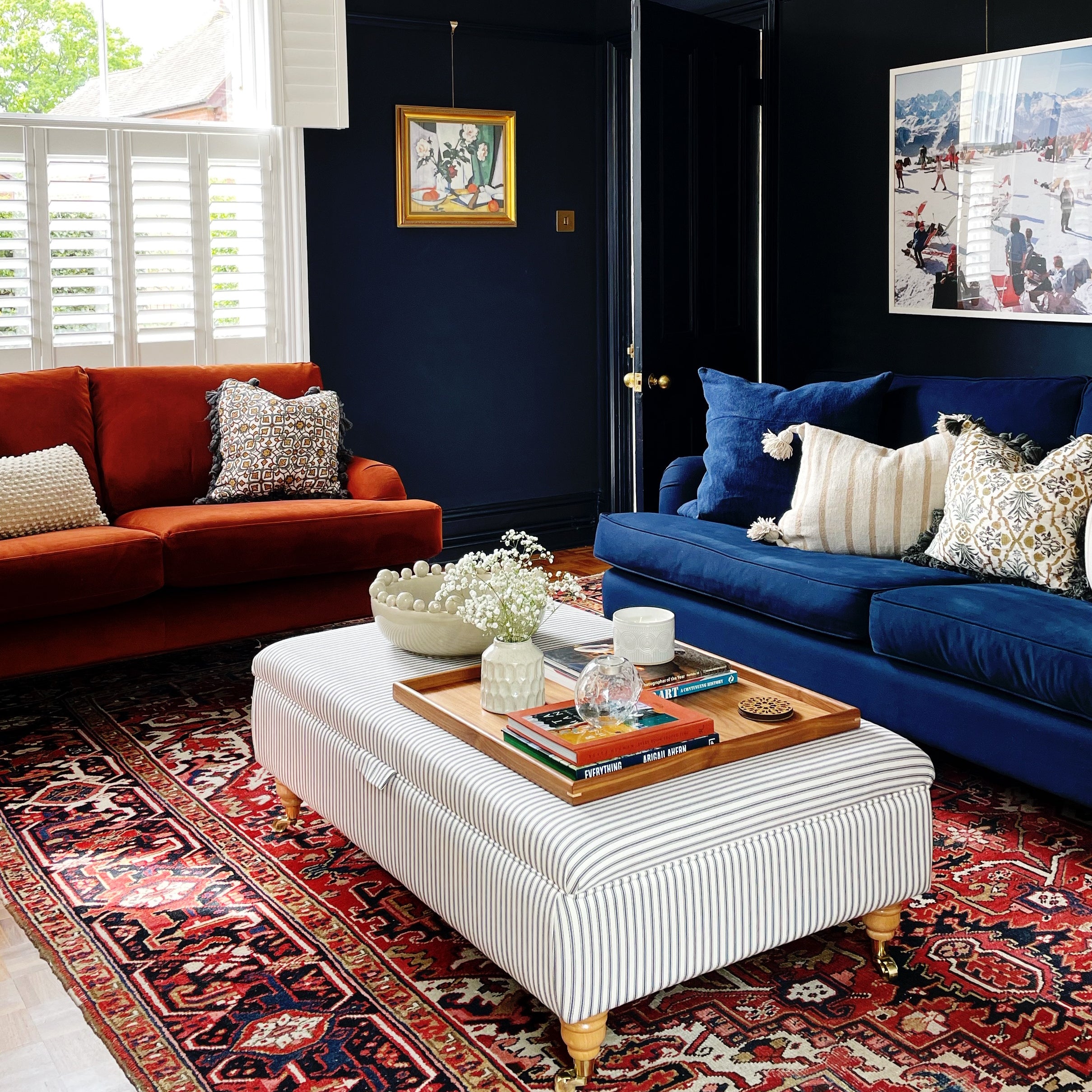 A wooden tray for footstool in a vibrant living room setting, styled with books, a candle, and flowers.