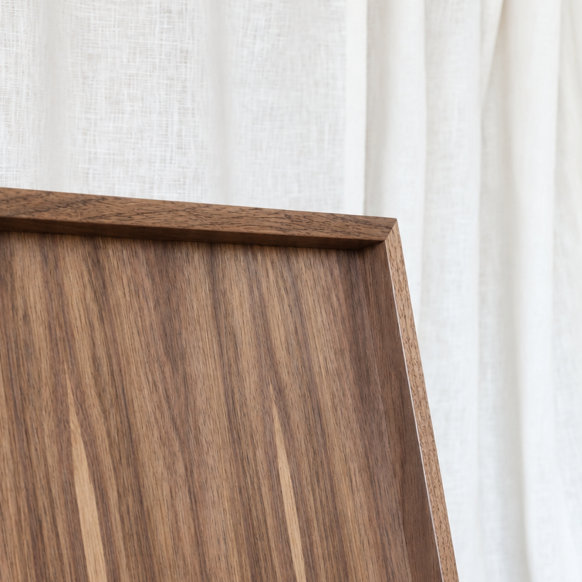 Close-up of a medium brown wood-grain tray corner with a white fabric curtain background.