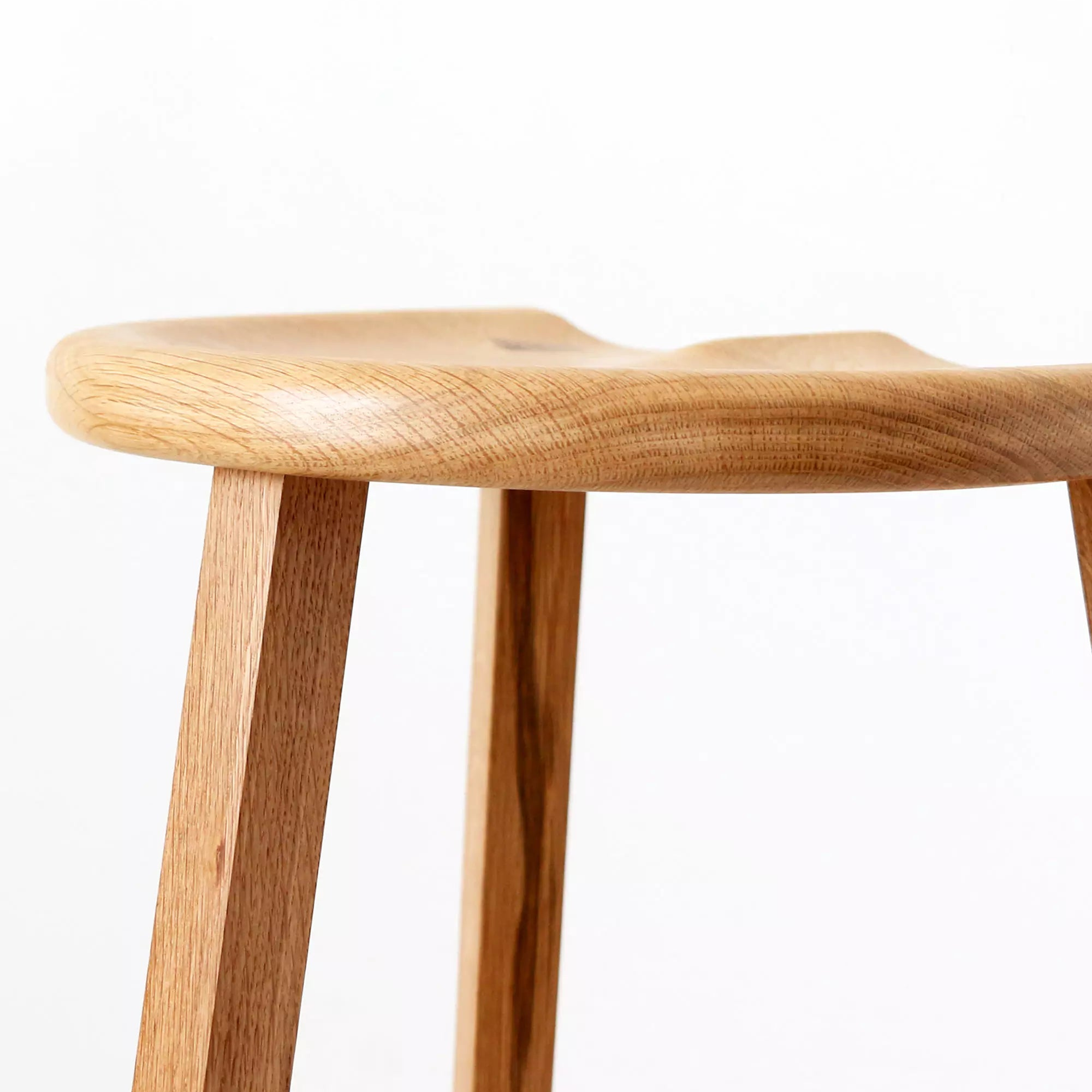 Wooden stool carved seat close-up with a white background