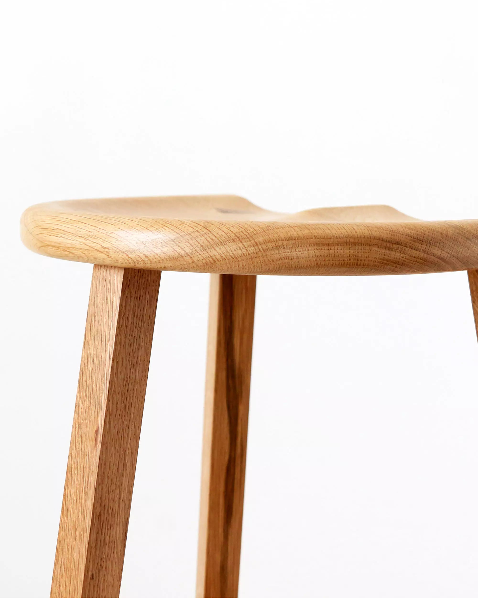 Wooden stool carved seat close-up with a white background