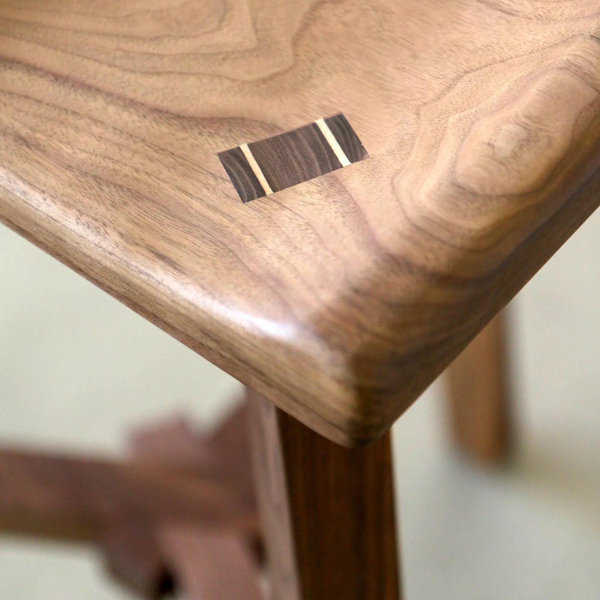 Wooden stool with a visible seat joinery detail on a blurred background