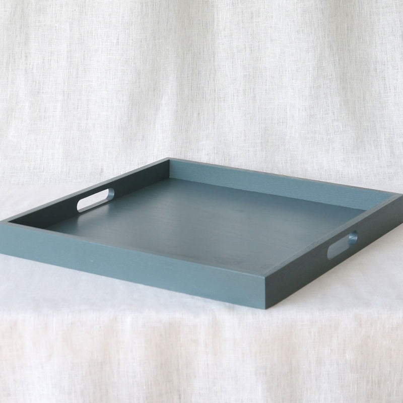 Diagonal angled view of the blue-grey ottoman tray showing both side handles and depth of the tray walls.