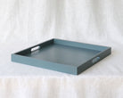 Diagonal angled view of the blue-grey ottoman tray showing both side handles and depth of the tray walls.