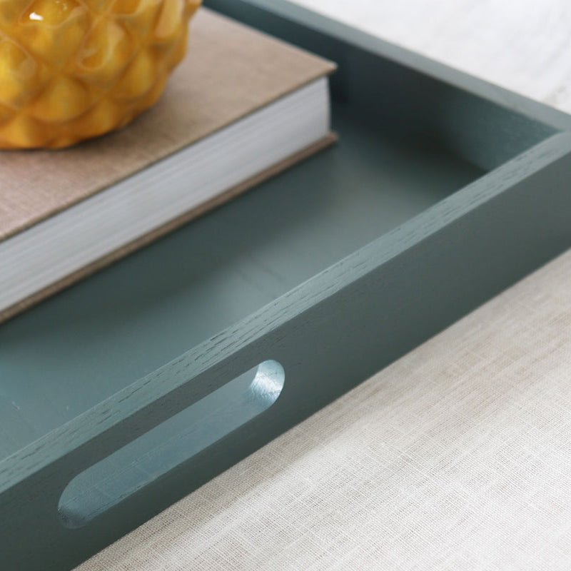 Detail view of the tray handle with a book and planter inside, showing the smooth finish and craftsmanship.