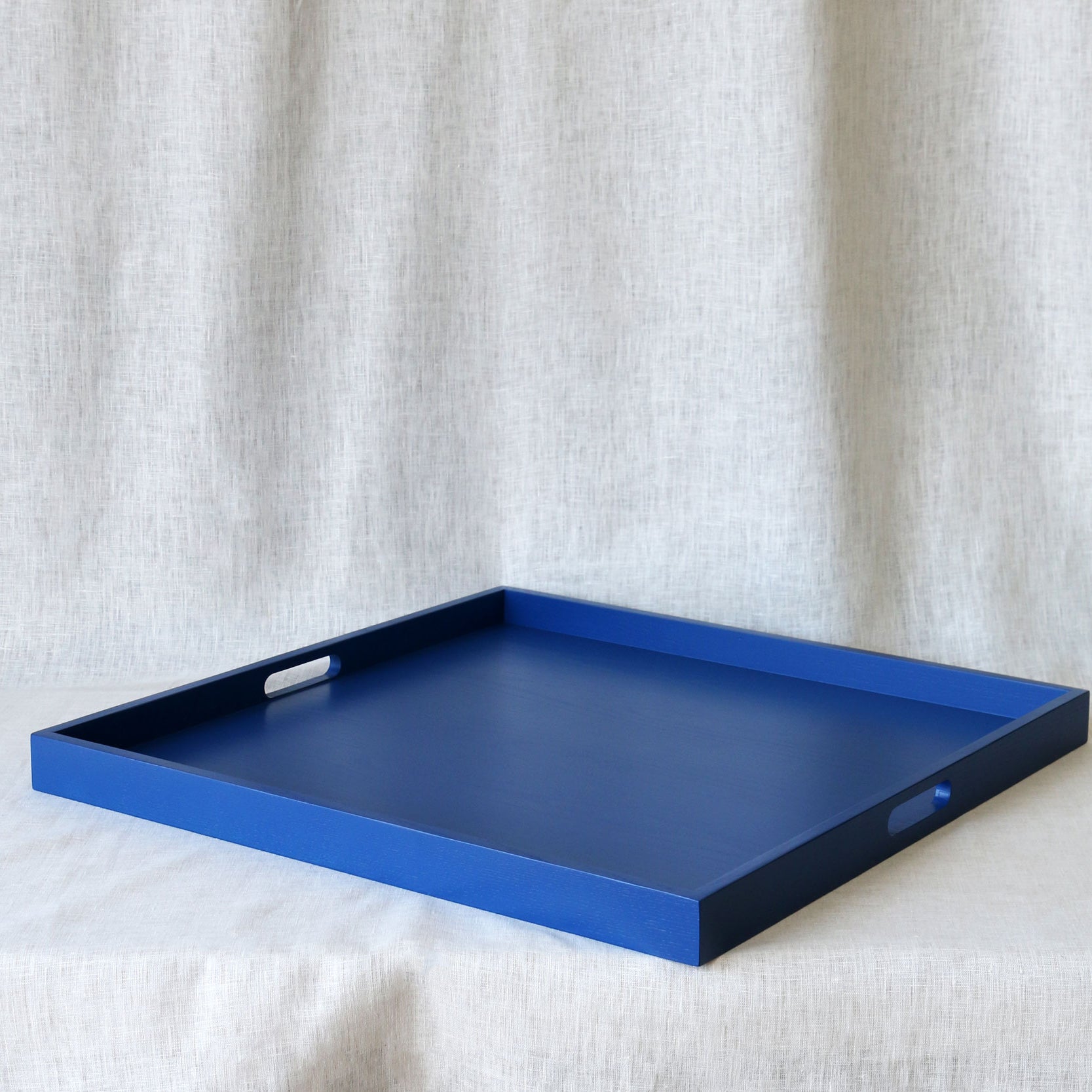Blue tray with handles on a textured white surface