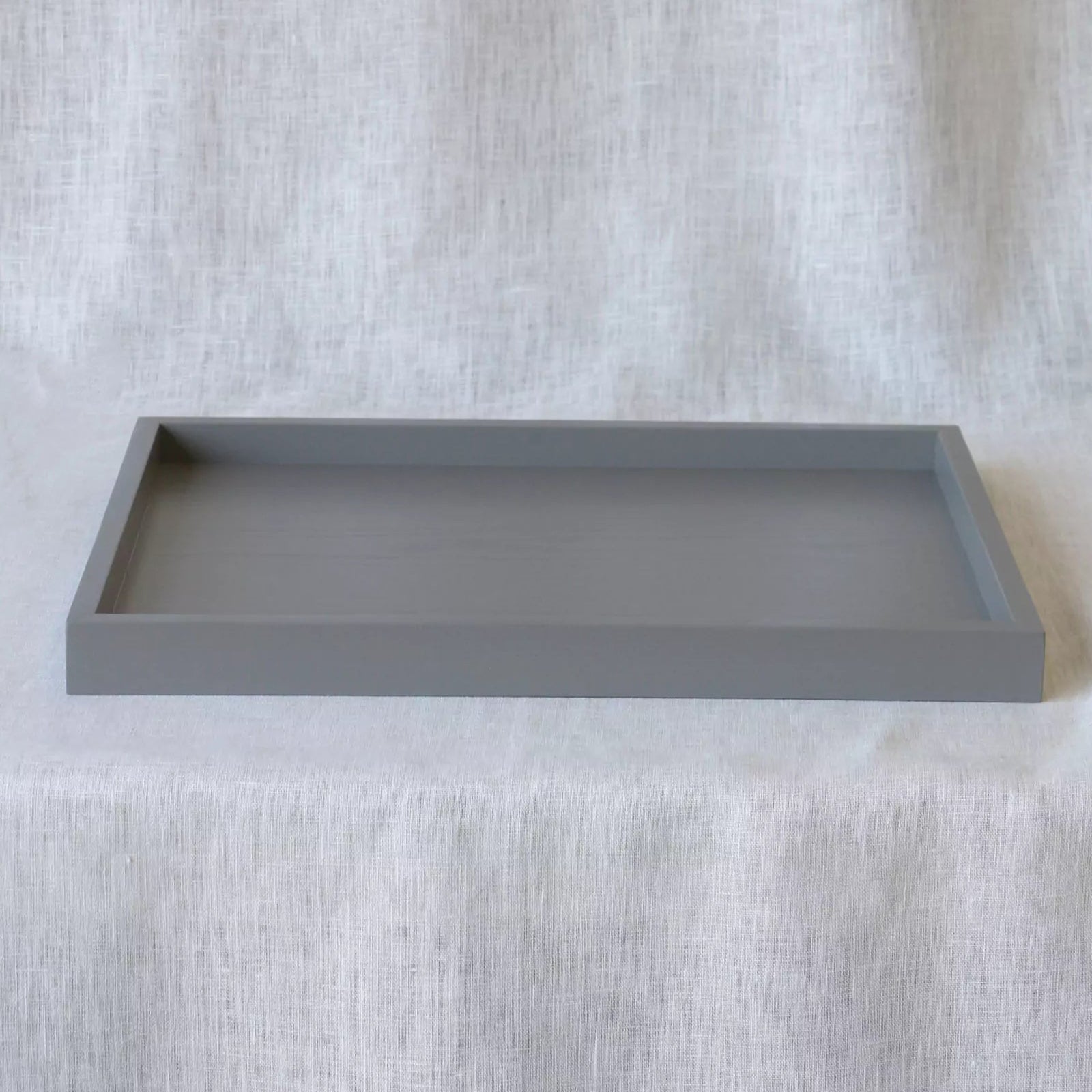 Gray rectangular tray on a textured white surface