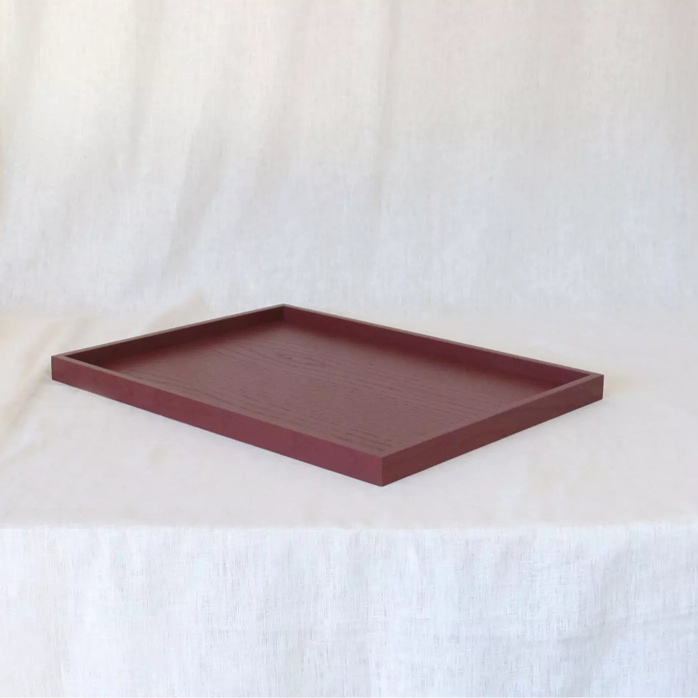 Maroon rectangular tray on a white curtain background