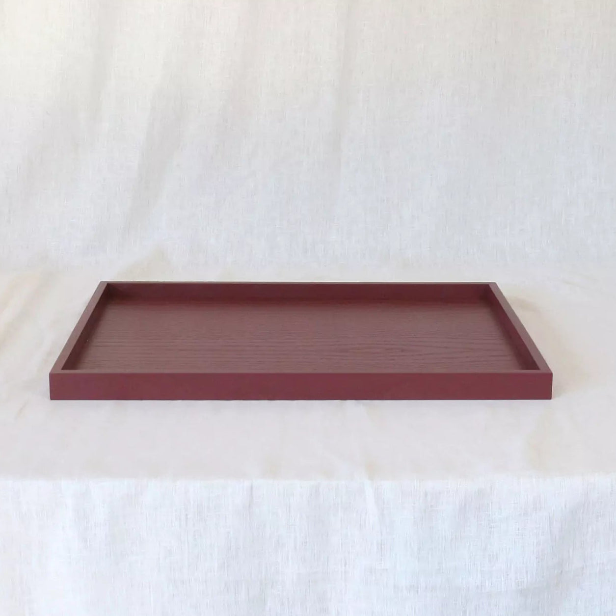 Maroon rectangular tray on a white fabric background