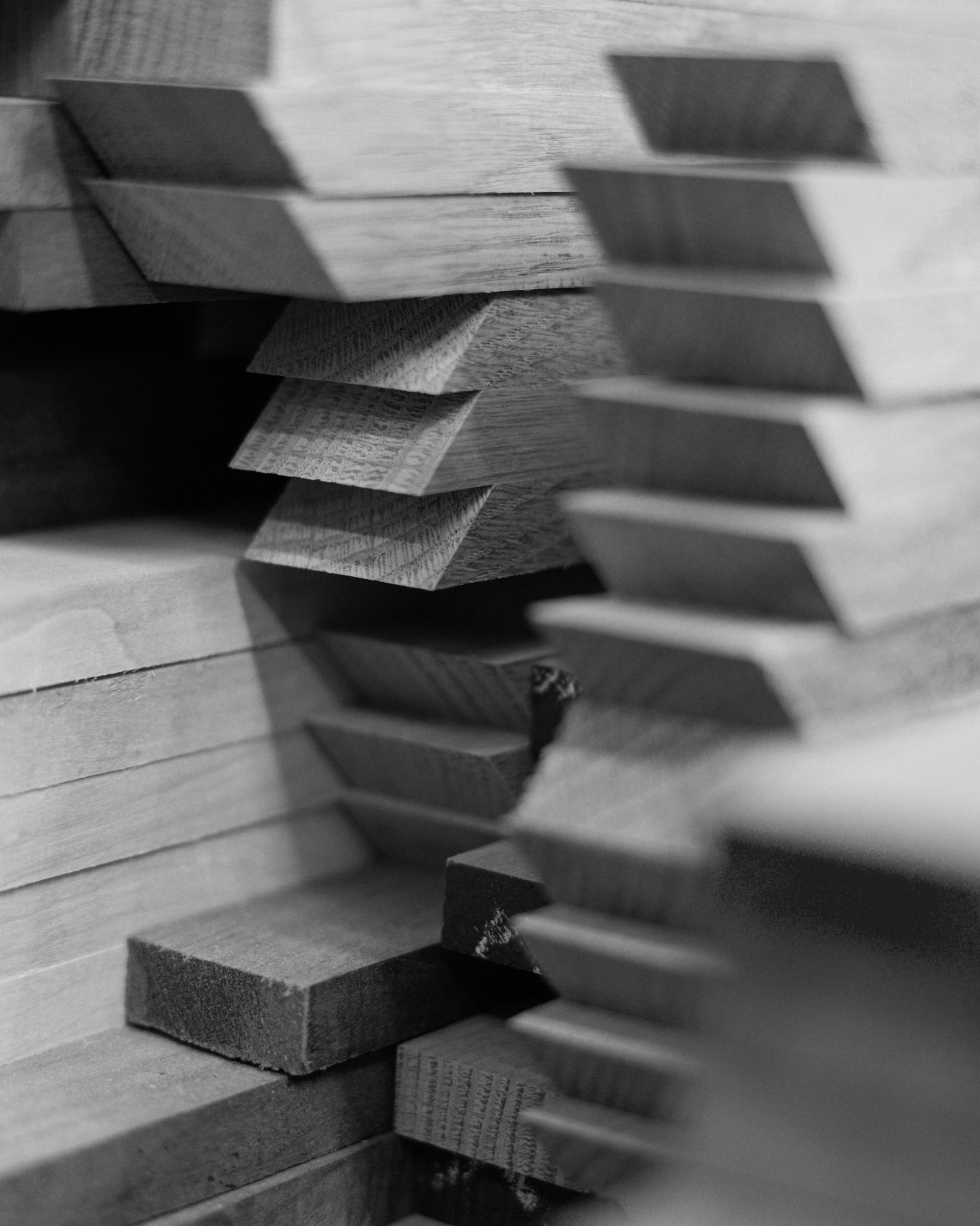 Stacked wooden pieces in a workshop, showcasing precision-cut panels ready to be assembled into high-quality handcrafted trays.