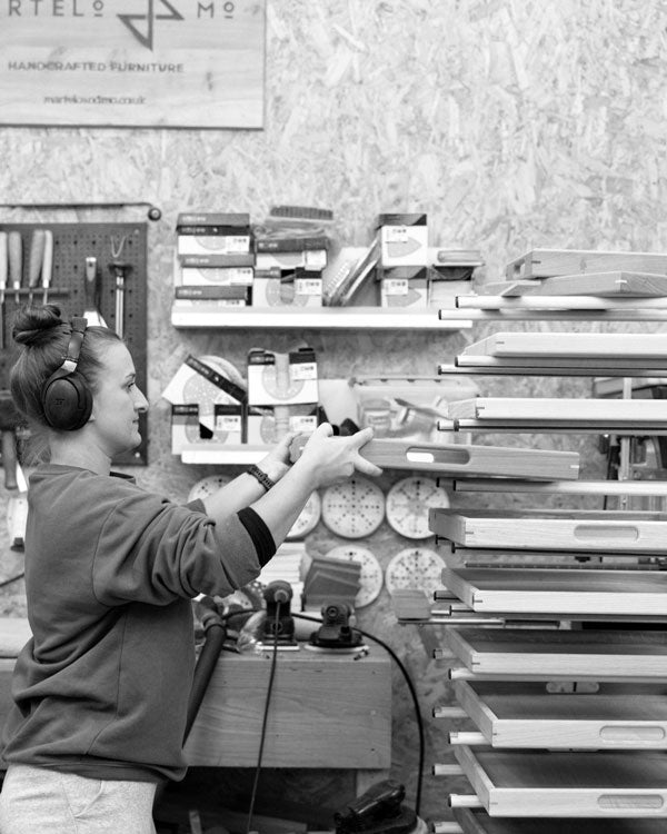 A craftswoman carefully placing handcrafted trays on a drying rack in a workshop, ensuring premium quality for each decorative tray.