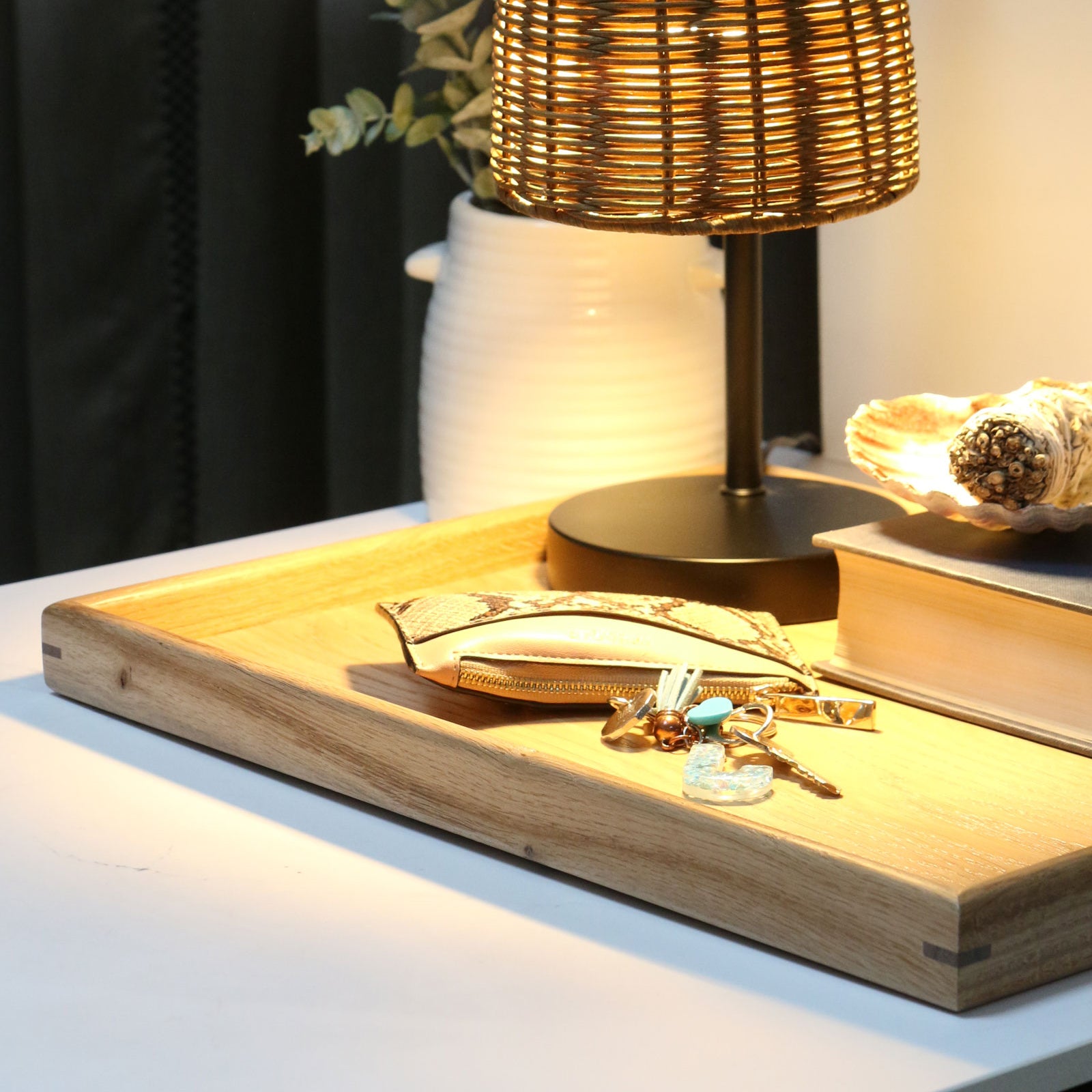 A handcrafted tray styled on a bedside table with books, keys, and a lamp, demonstrating its functionality as a stylish decorative tray.