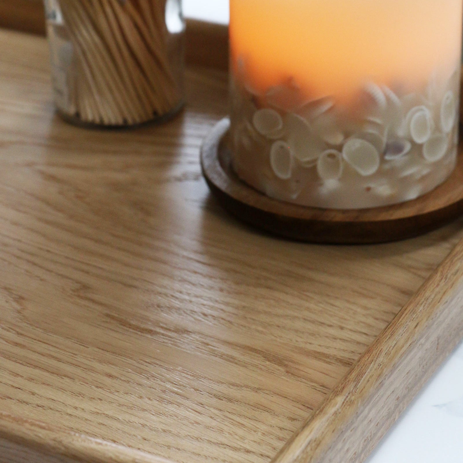 A decorative tray with a warm candlelit setting, used for organizing everyday essentials in a cozy interior space.