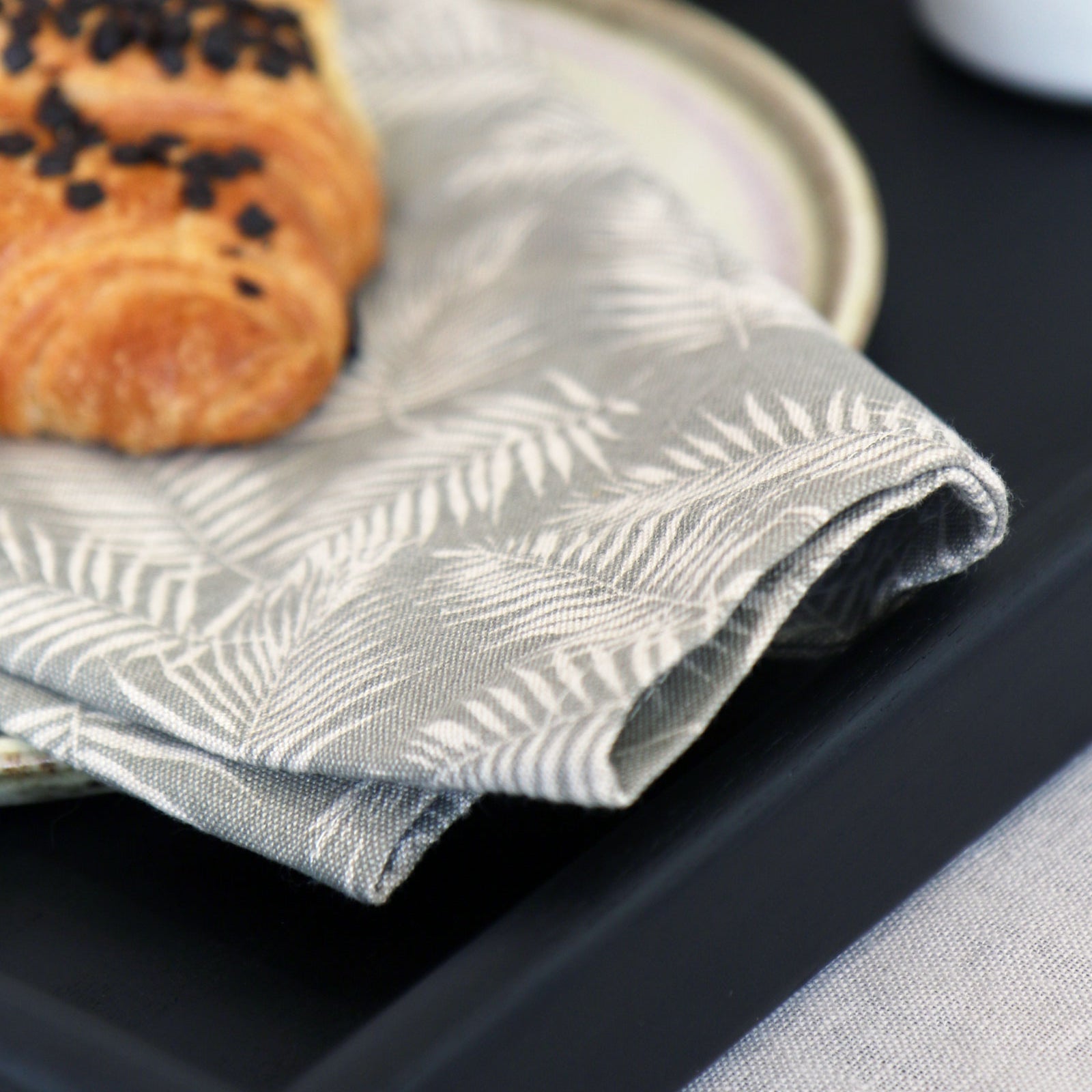 Decorative tray displaying intricate details of a napkin with delicate leaf prints placed on its surface, emphasizing the elegant craftsmanship.