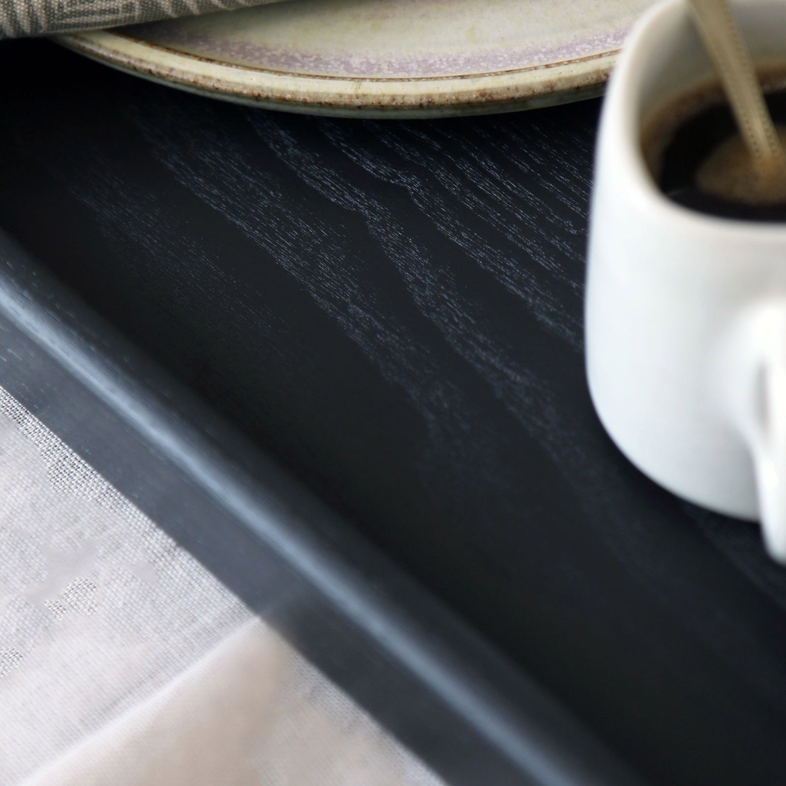 A detailed view of the textured wooden surface of a coffee table tray, capturing its natural grain and high-quality black wood finish.