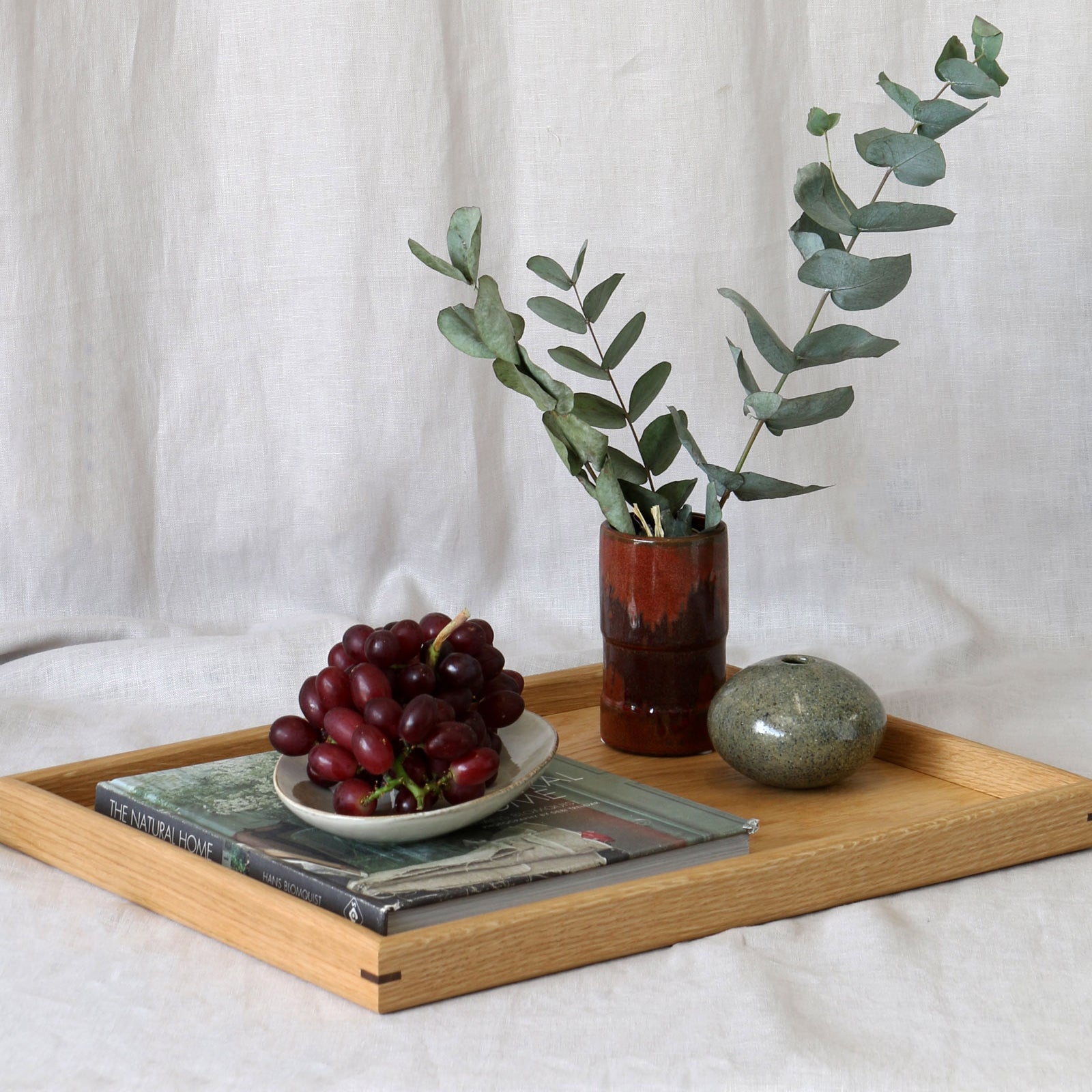 A decorative tray styled with books, a ceramic vase, and fresh greenery, perfect as a wooden tray for footstool or a coffee table tray.