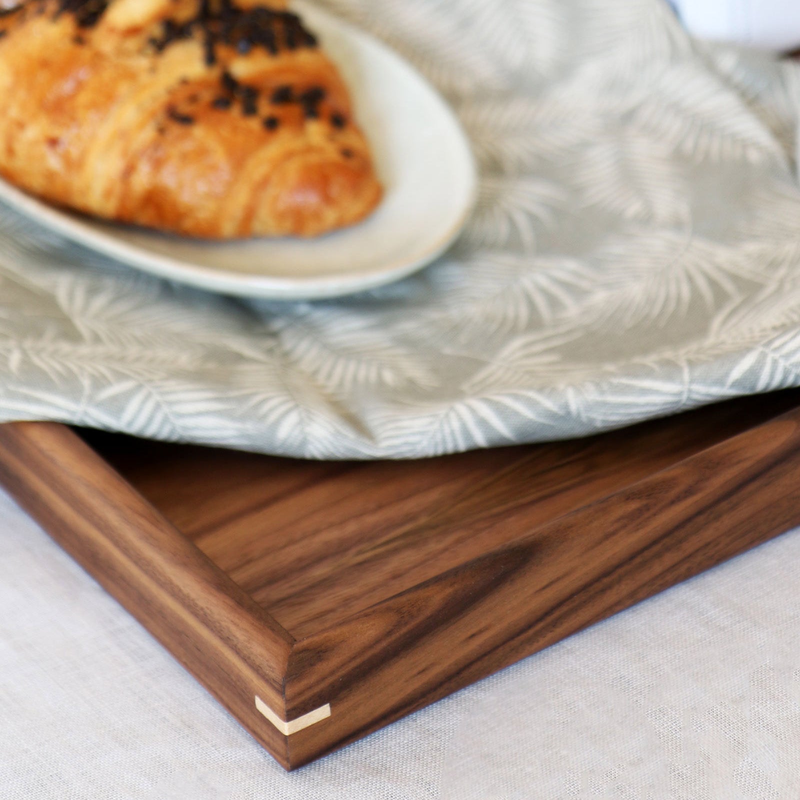 A coffee table tray styled with breakfast essentials, including a croissant, coffee, and fresh fruit.