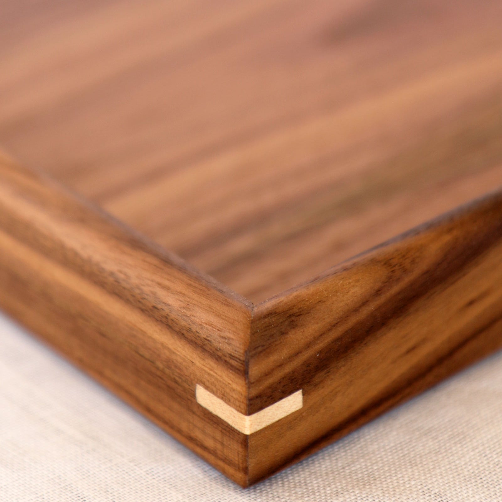 A close-up of the fine joinery and polished walnut surface of a wooden tray for footstool.