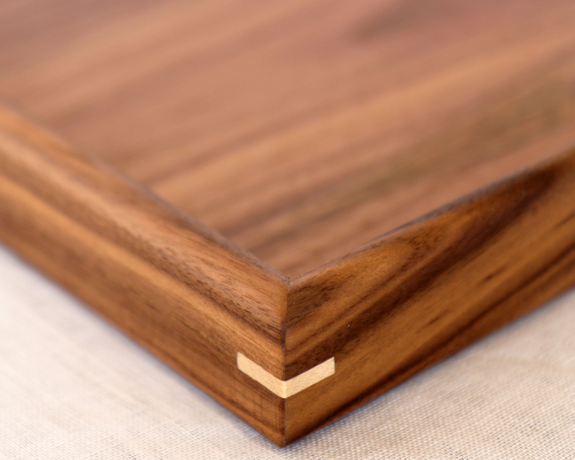 A close-up of the fine joinery and polished walnut surface of a wooden tray for footstool.