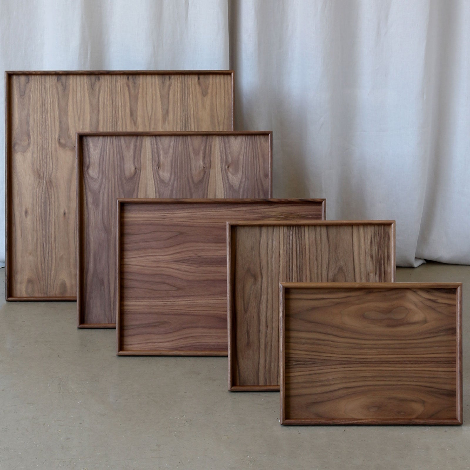 A set of handcrafted trays in walnut wood, displayed in multiple sizes, perfect as a wooden tray for footstool or a coffee table tray.