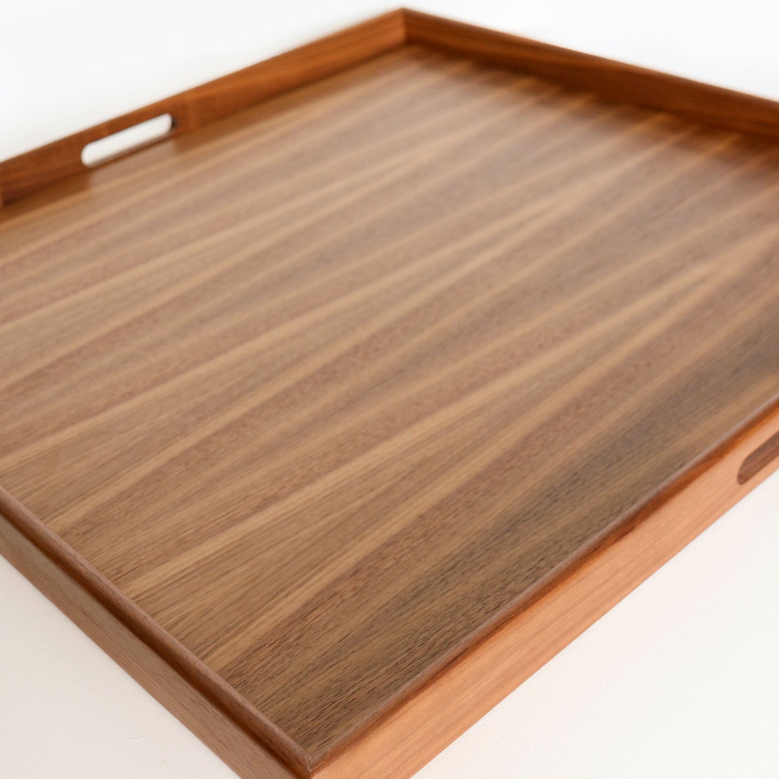 A large decorative tray in walnut with smooth, natural grain and built-in handles, designed for both function and style.