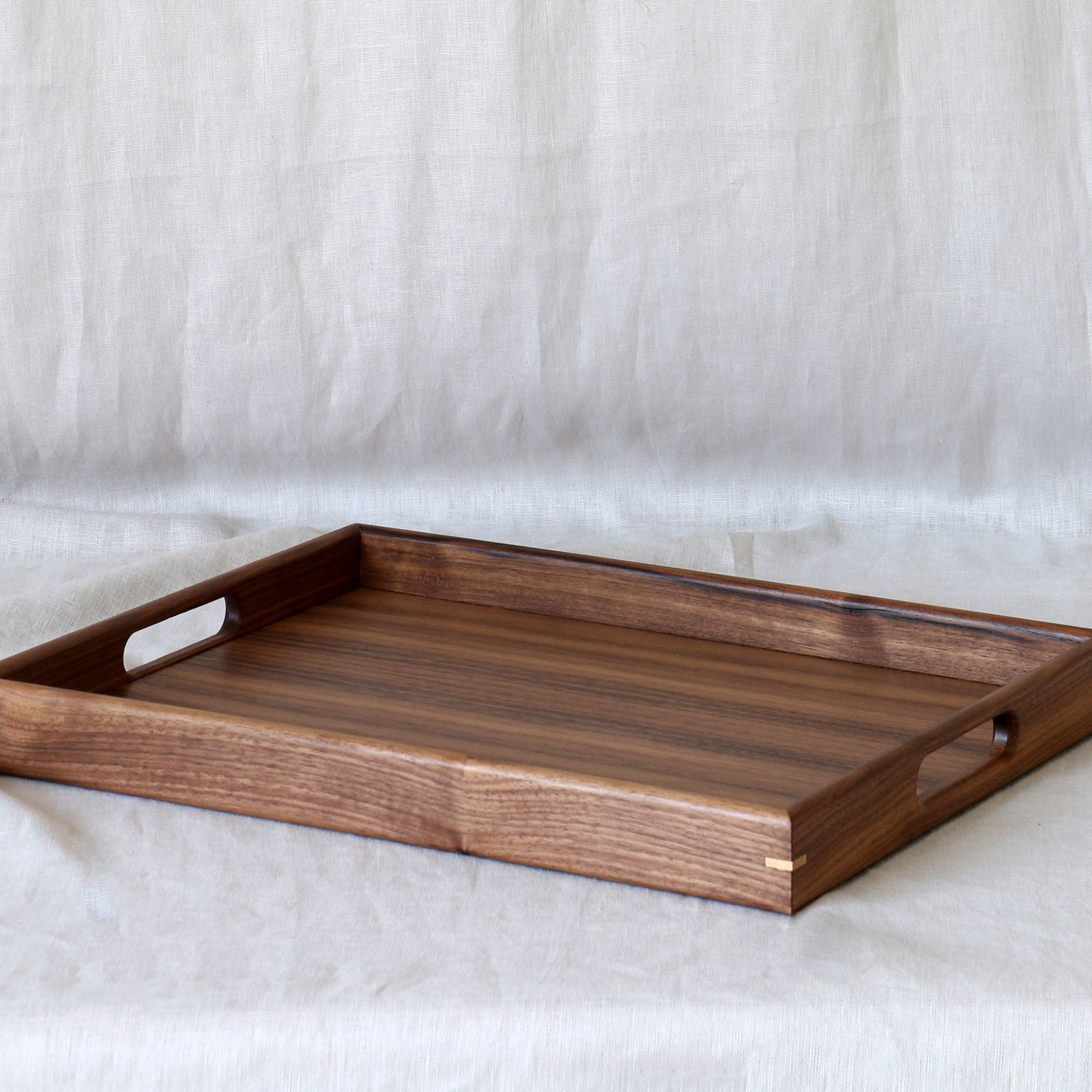A walnut coffee table tray with elegant curved handles and a polished surface, ideal for serving or decorating a living space.