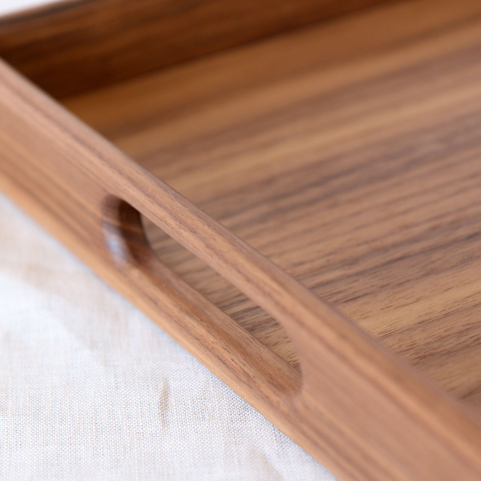 A close-up of a decorative tray in walnut, highlighting the precisely cut handle and fine craftsmanship.