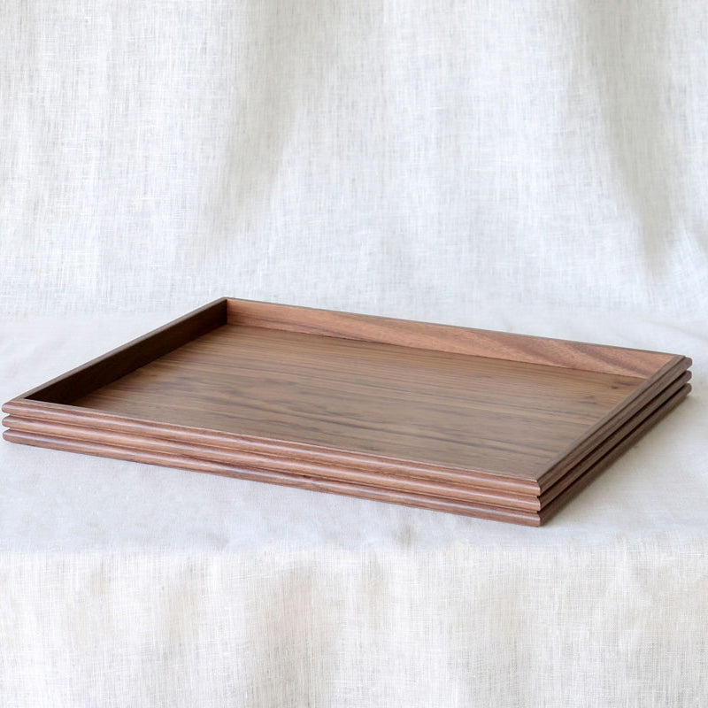 Slightly angled top-down view of the empty walnut wooden tray, emphasizing the natural wood grain and minimalist raised edge.