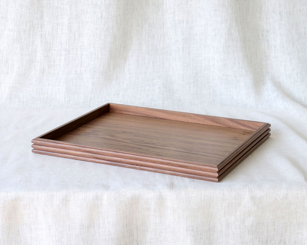 Slightly angled top-down view of the empty walnut wooden tray, emphasizing the natural wood grain and minimalist raised edge.