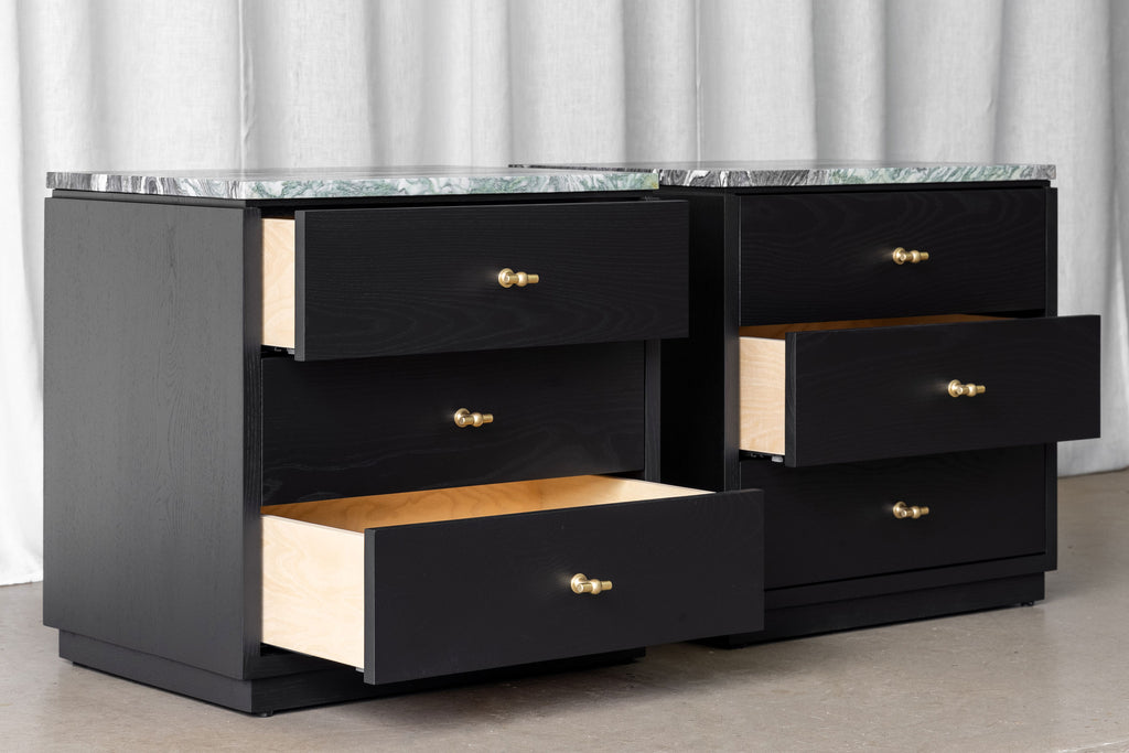 Pair of black wooden bedside cabinets with 3 drawers each, brass T-shaped handles and marble tops