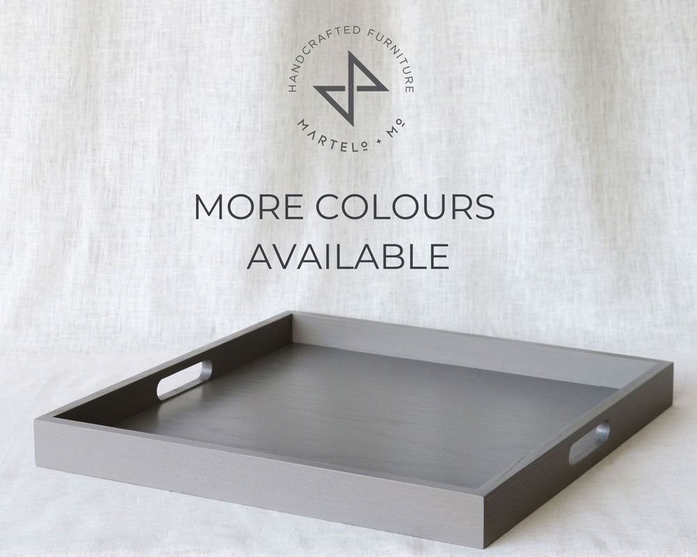 Grey ottoman tray with cut-out handles, displayed on a fabric backdrop with the Martelo & Mo logo and “More Colours Available” text.