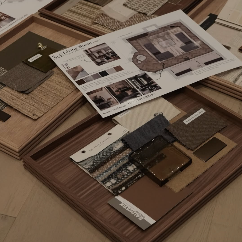 A styled flat-lay of multiple wooden furniture design boards and material swatch collections on a light wood floor. Several boards contain fabric, wood, and finish samples, with one board featuring printed room design sketches and a visible 'MADE IN ITALY' label.