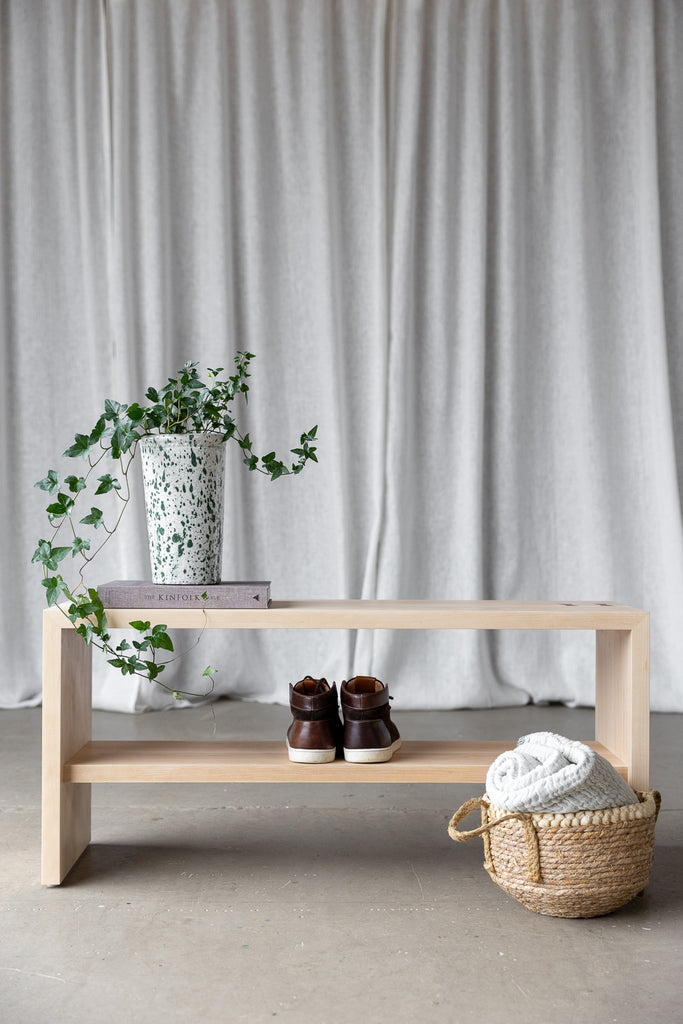 lifestyle image of the bench styled with ivy plant, book and shoes