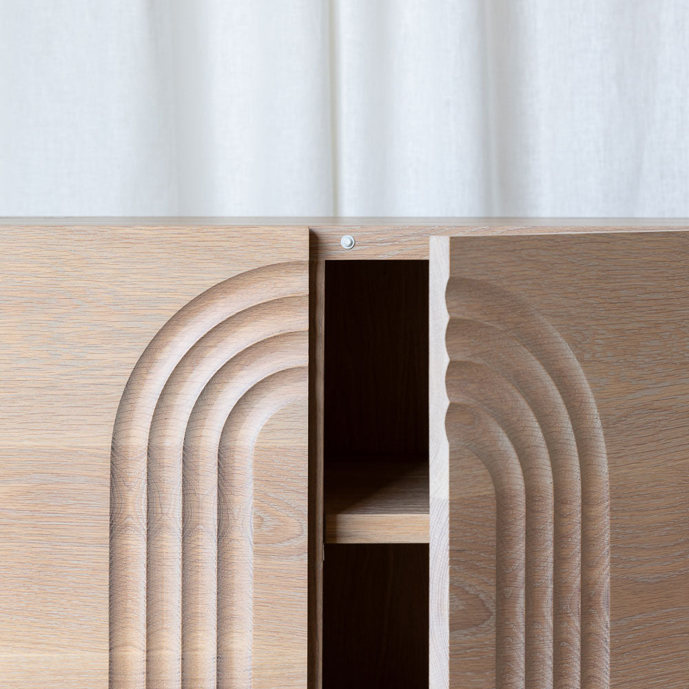 close-up view of the tv stand oak door fronts with the carved arch details, and the push-to-open doors