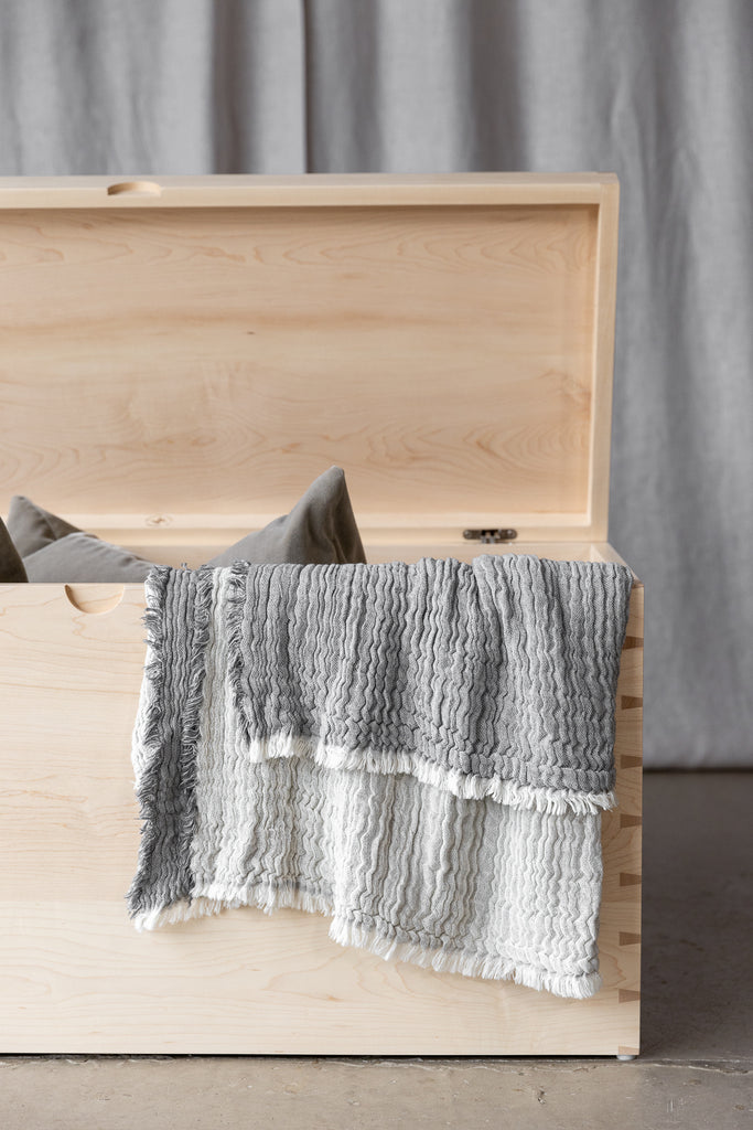 A close-up view of the Maple Storage Chest styled with cushions and a blanket, offering both practical storage and functionality.
