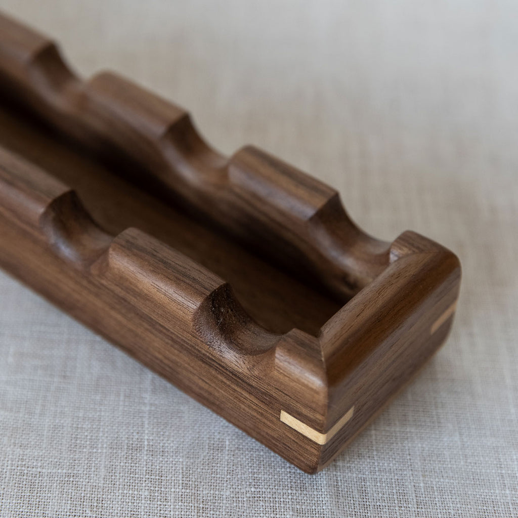Close-up of a walnut wooden tray for oval canapés. The tray has a contrasting wood corner detail.