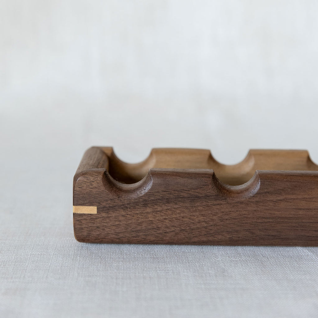 Close-up of a walnut wooden tray for oval canapés. The tray has a contrasting wood corner detail.