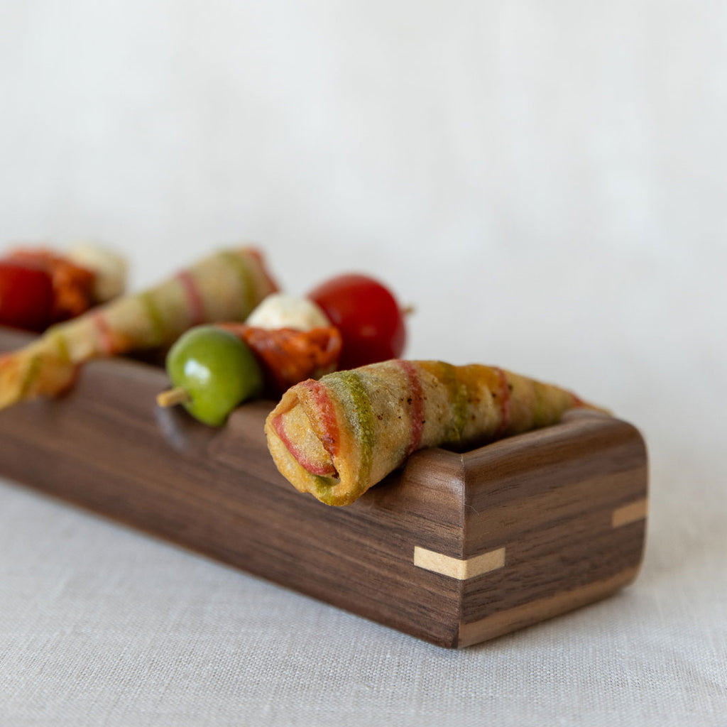 Close-up of a walnut wooden tray for oval canapés and nibbles.