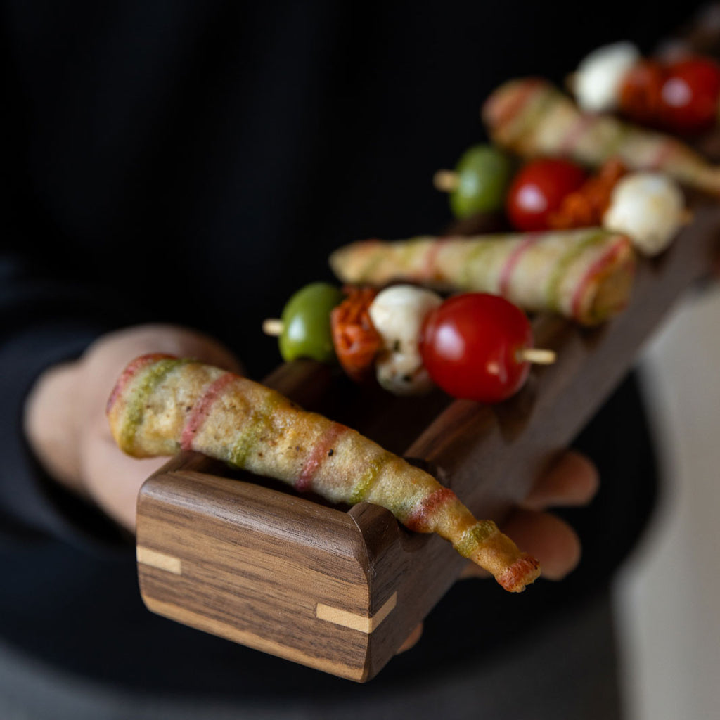 Long walnut wooden canapé's serving tray with oval-shaped canapés