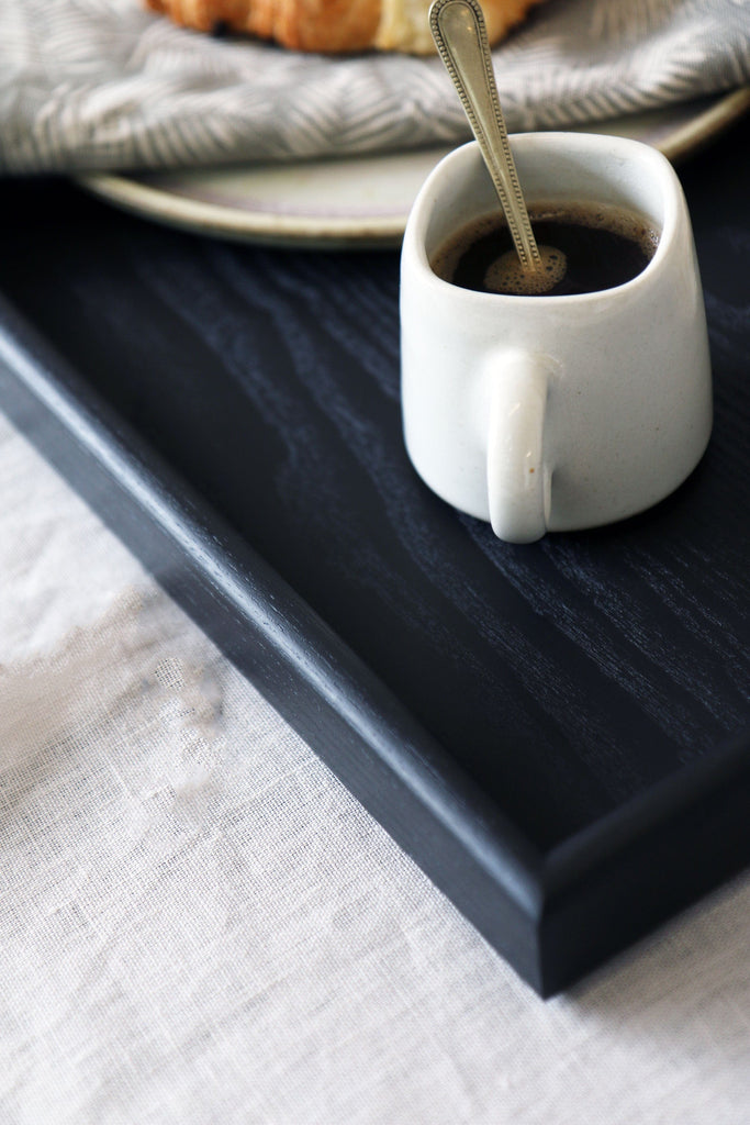 Close-up of a corner of the black wooden serving tray by Martelo and Mo.