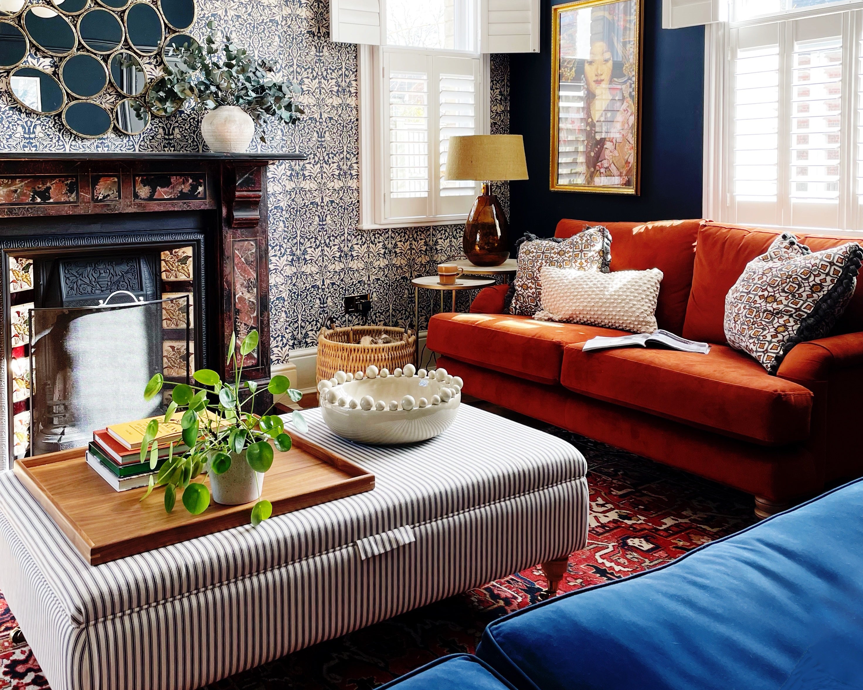 A wooden tray for footstool in a stylish living room, featuring books, a potted plant, and decorative elements on an ottoman.