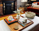 A handcrafted tray used as a coffee table tray, beautifully arranged with books, candles, and ceramics in a living room.