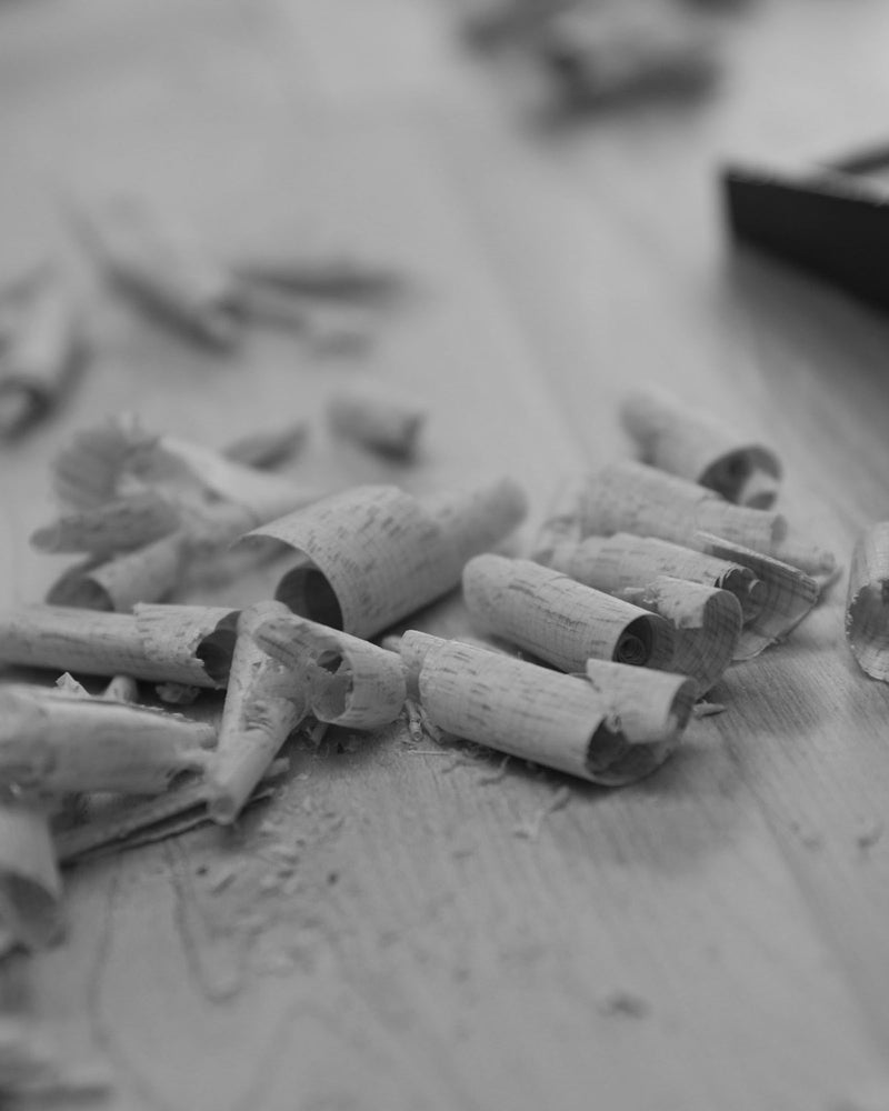 Wood Shavings from Hand Planing – A collection of curled wood shavings scattered on a wooden surface, highlighting the process of traditional woodworking.