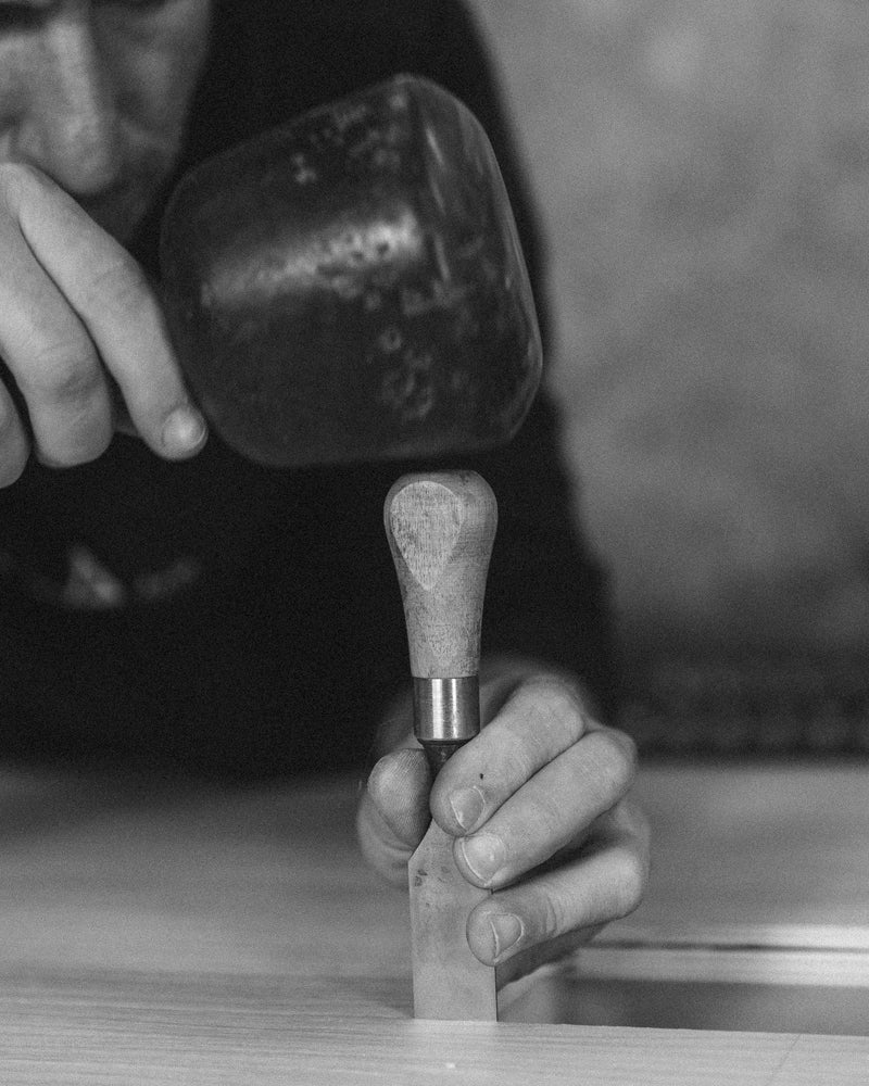 Woodworker Carving with Chisel and Mallet – A craftsman using a mallet and chisel to shape wood, demonstrating skilled handcrafting techniques.