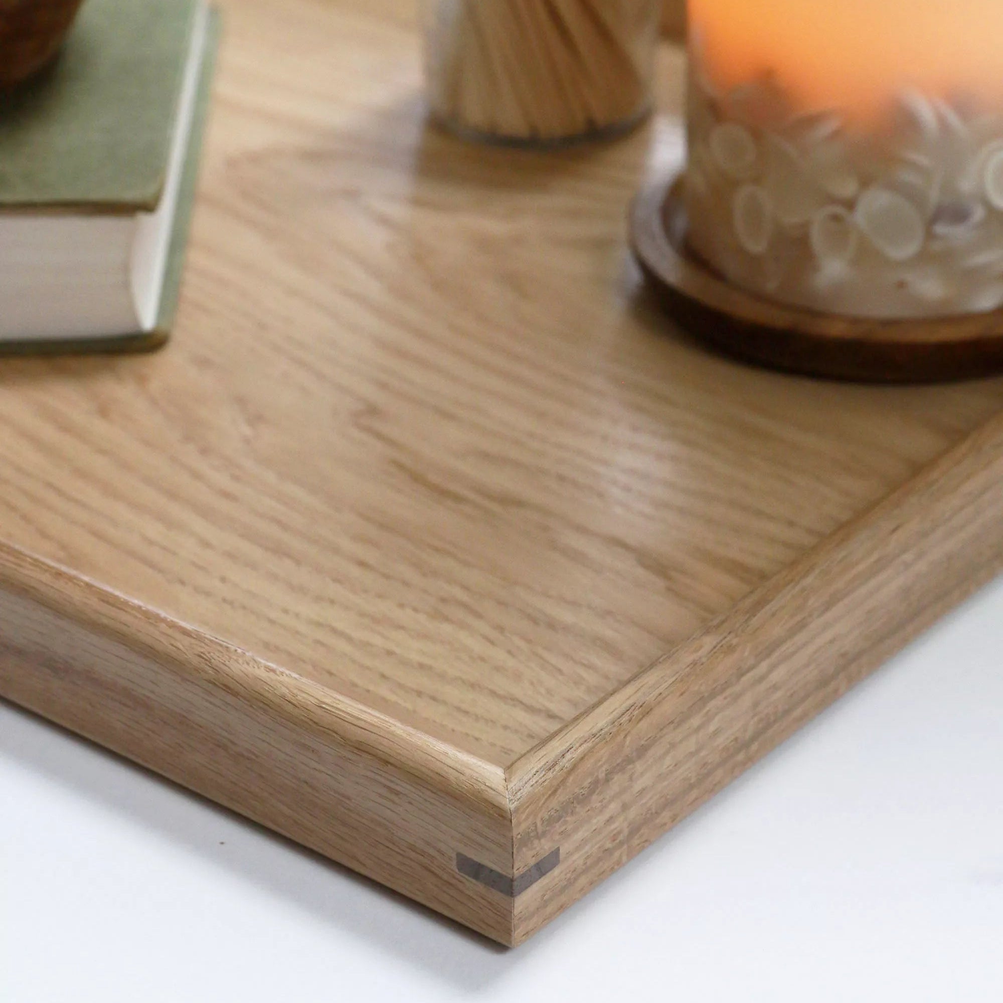 A decorative tray with a warm candlelit setting, used for organising everyday essentials in a cosy interior space.