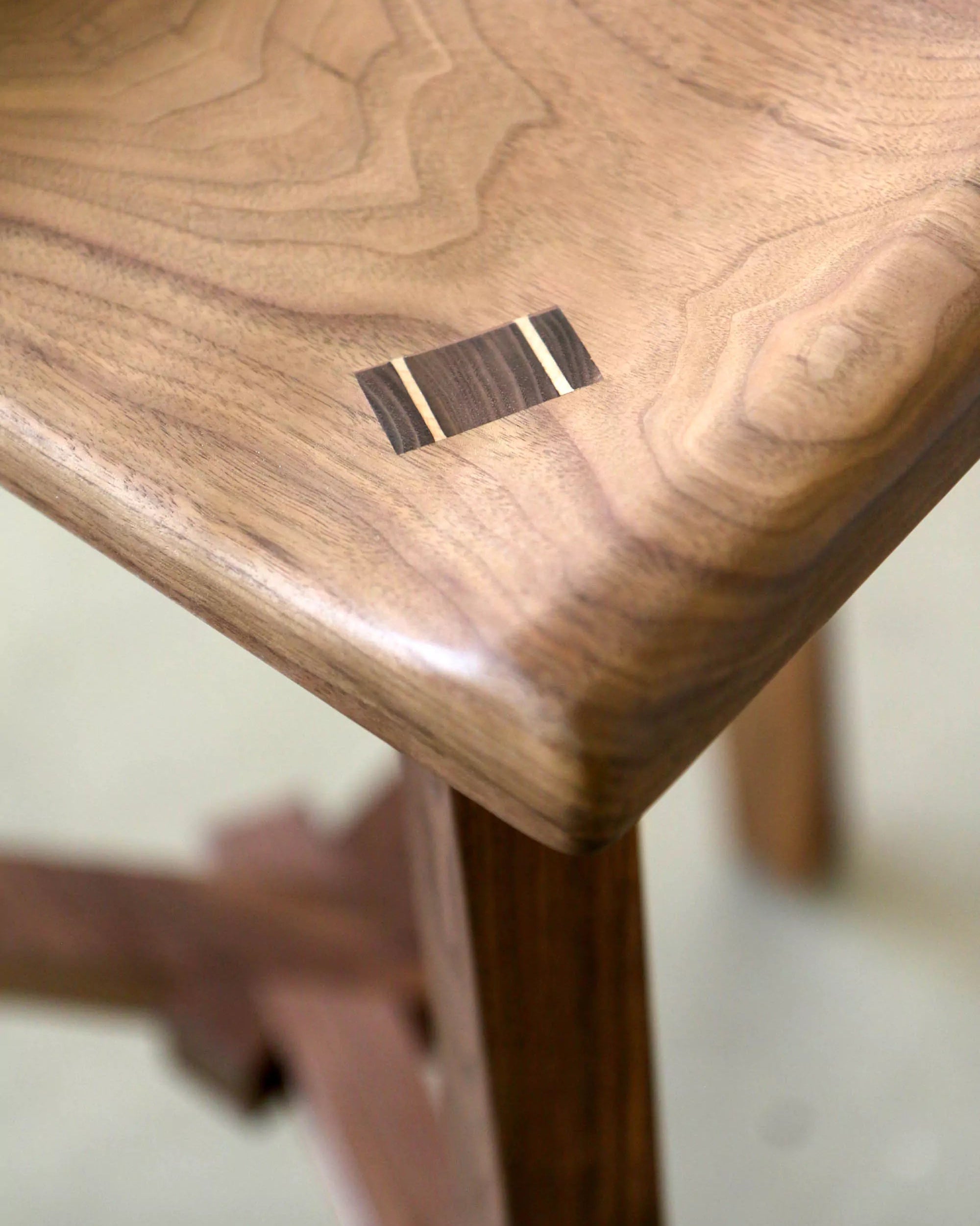 Wooden stool with a visible seat joinery detail on a blurred background