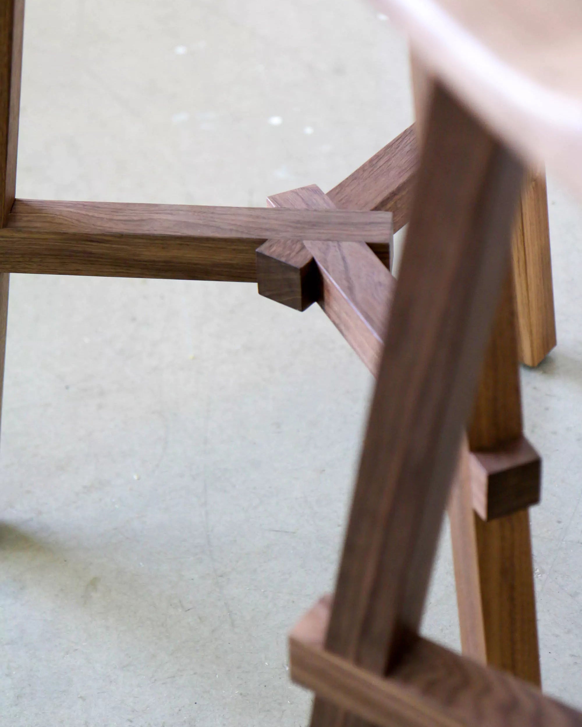 Close-up of a wooden stool frame on a light-colored floor.