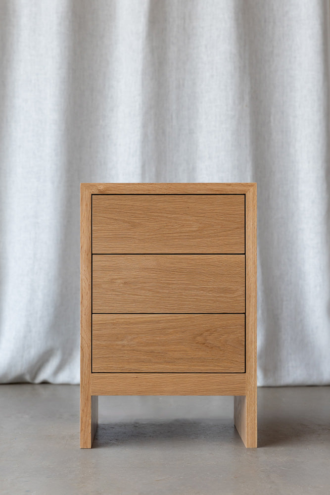 front view of the Gaia bedside cabinet with 3 drawers in oak hardwood