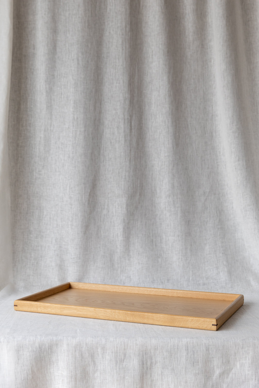 side view of the oak ottoman tray showcasing contrasting walnut corner detail pins